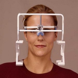 Paziente durante un esame di kinesiografia mandibolare computerizzata con l'elmetto leggero a sensori magnetici per l'analisi dei movimenti.
